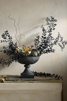 a black vase filled with lots of different types of flowers and plants on top of a table