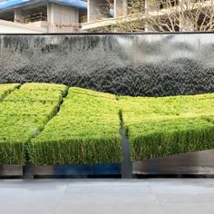 a bench made out of grass in front of a wall with water running down it