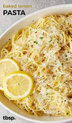 a plate of pasta with lemon and parmesan cheese on top, next to a slice of lemon