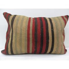 an old striped pillow is sitting on a white surface with a black and red stripe pattern