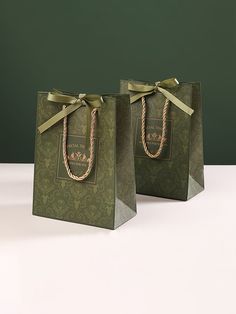 two green bags with bows on them sitting on a white counter top next to each other