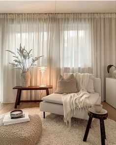 a living room filled with furniture and a large window covered in white drapes