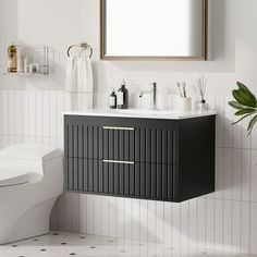 a white toilet sitting next to a black and white sink in a bathroom under a mirror