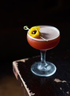 a cocktail with an olive garnish on the top