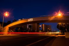 an illuminated bridge over a city street at night