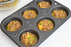 a muffin tin filled with some taco meat and cheese in it next to a glass bowl