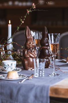 an easter bunny figurine sitting on top of a table next to some glasses