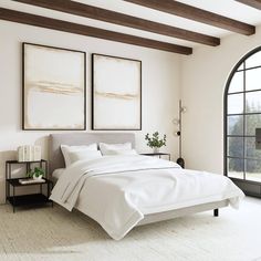 a large bed sitting in a bedroom next to two framed pictures on the wall above it