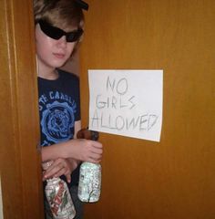 a young boy wearing sunglasses holding two empty beer bottles in front of a sign that says no girls allowed