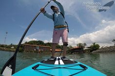 a man standing on top of a blue boat in the water with his arms up