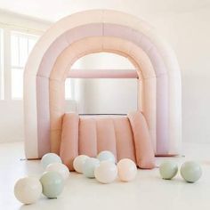 an inflatable arch with pastel colors and balloons on the floor next to it