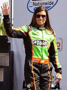 a man in a racing suit waves to the crowd