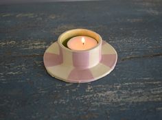 a pink and white candle sitting on top of a saucer