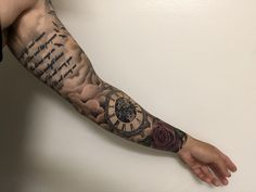 a man's arm with a clock and roses tattoo on the left forearm, which is also in roman numerals