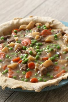 a pie with peas, carrots and meat in it on a blue platter