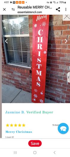 a red christmas sign sitting on the side of a brick building next to a window