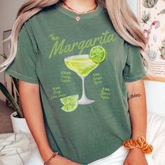 Vintage style margarita shirt with the ingredients listed. About our T-shirts: Comfort Colors introduces its garment-dyed t-shirt; a fully customizable tee made 100% with ring-spun cotton. The soft-washed, garment-dyed fabric brings extra coziness to your wardrobe while the relaxed fit makes it an excellent daily choice. The double-needle stitching throughout the tee makes it highly durable while the lack of side-seams helps the shirt retain its tubular shape. Sizing Chart: Use the sizing chart to understand the measurement of our T-Shirts. For the oversized look, please size up. Return policy:  We do not accept returns unless items are damaged. This is due to our shirts being custom made-to-order. Cinco De Mayo Funny Print Crew Neck Top, Cinco De Mayo Cotton Tops With Funny Print, Cinco De Mayo Funny Print Cotton Tops, Cotton Tops With Funny Print For Cinco De Mayo, Cinco De Mayo Graphic Tee With Short Sleeves, Cinco De Mayo Graphic Tee With Crew Neck, Cinco De Mayo Graphic T-shirt, Cotton Tops With Graphic Print For Cinco De Mayo, Cocktail Tshirt