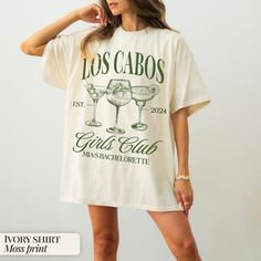 a woman wearing a t - shirt that says los cabos with two martini glasses on it