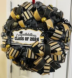 a black and gold graduation wreath hanging on a door with congratulations class of 2020 written on it