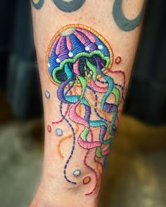 a colorful tattoo on the leg of a person with an octopus and jellyfish design