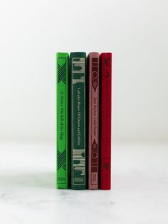 three books sitting on top of each other in front of a white wall and floor