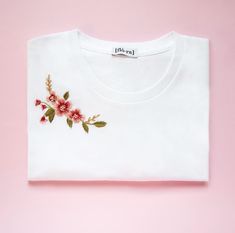 a white t - shirt with pink flowers on it