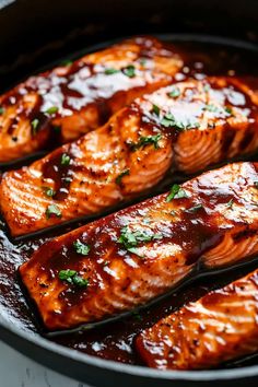 salmon fillets in a skillet with sauce and parsley