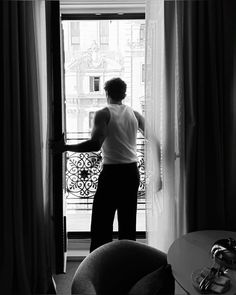 a man standing in front of a window looking out