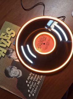 a record player sitting on top of a wooden table next to a book and headphones