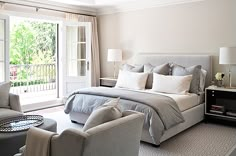 a bedroom with a large bed and two chairs in front of a sliding glass door