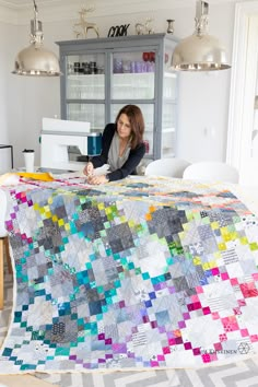 a woman sitting at a table with a quilt on it