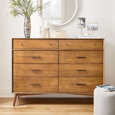 a large wooden dresser sitting in front of a round mirror on top of a wall