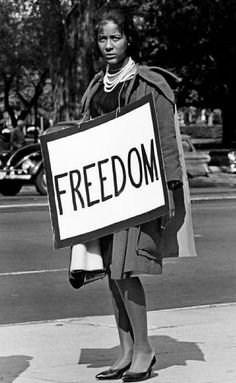 a black and white photo of a woman holding a sign that says, freedom