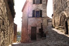 an alley way with stone buildings and cobblestone streets in the sun shining through windows