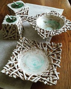 three white bowls sitting on top of a wooden table next to candles and napkins