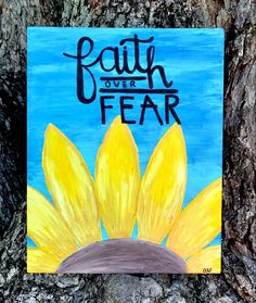 a painting of a sunflower on a tree with the words faith over fear painted on it