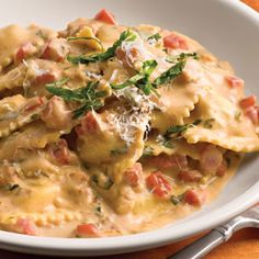 a white bowl filled with pasta covered in sauce and cheese on top of an orange napkin