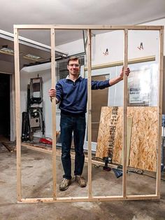 a man standing in front of a wooden frame