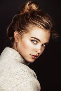 a beautiful young woman with blue eyes wearing a turtle neck sweater and looking into the camera