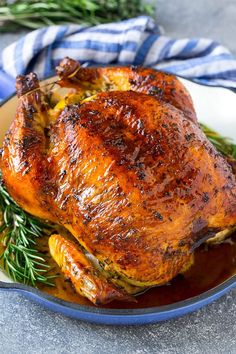 a roasted chicken on a plate with rosemary garnish