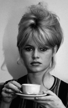 a woman sitting on a couch holding a cup and saucer