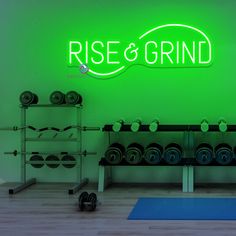 there is a gym with exercise equipment in front of the neon sign that reads rise and grind