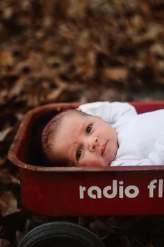 a baby is laying in a red wagon