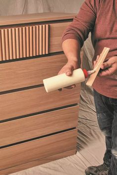 a man is holding a roll of paper and rolling it on top of a dresser