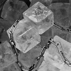 a black and white photo of some ice cubes with chains attached to the sides