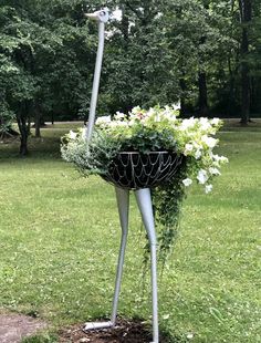 a metal planter with flowers in it sitting on top of a grass covered field