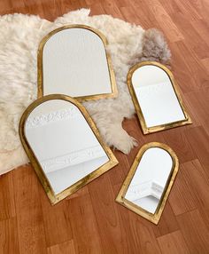 three mirrors sitting on top of a wooden floor next to a white sheepskin rug