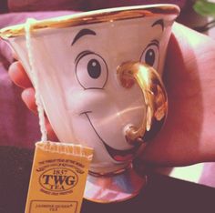 a person holding a coffee cup with a face drawn on it and a tag attached to the mug