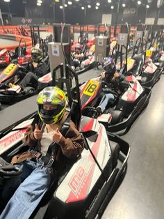 a row of go karts lined up in an indoor area with people sitting on them