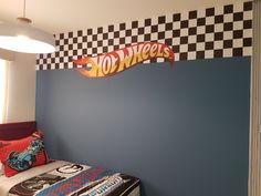 a bed room with a checkered wall and a hot wheels sign on the wall